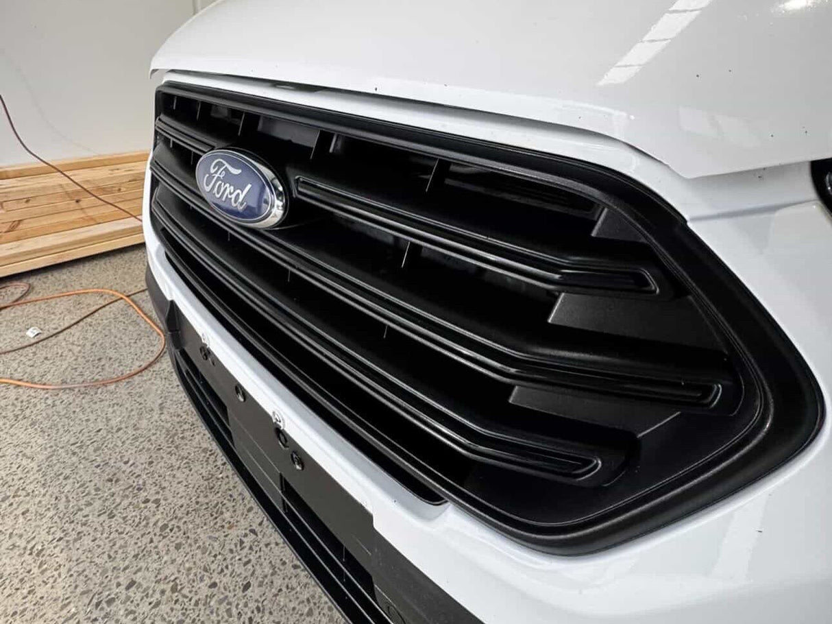 Close-up of a Ford car grille with a white car body and black grille.