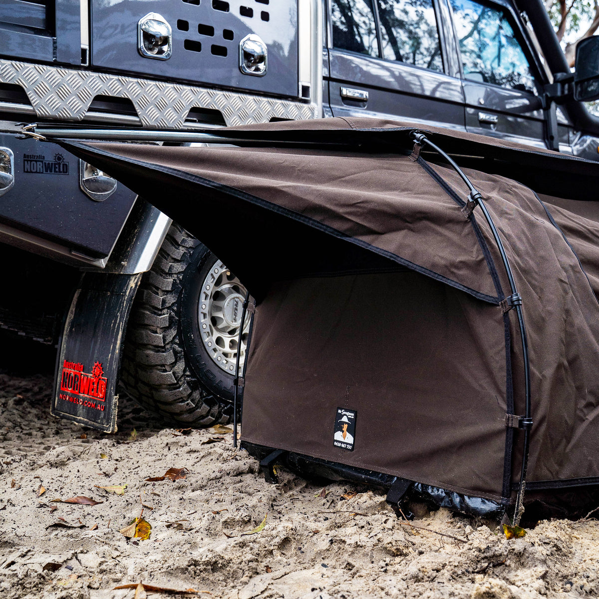 Close-up of the Ultimate King Single Swag's hoop pole and canvas beside a 4WD wheel
