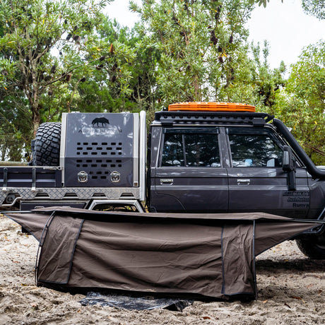 Ultimate King Single Swag pitched on sand beside a Land Cruiser ute with a steel canopy