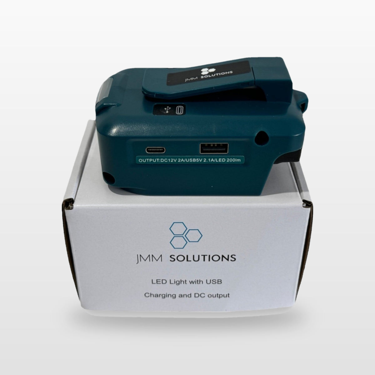 Makita-compatible USB & 12V Charger with LED Light: standing on its box
